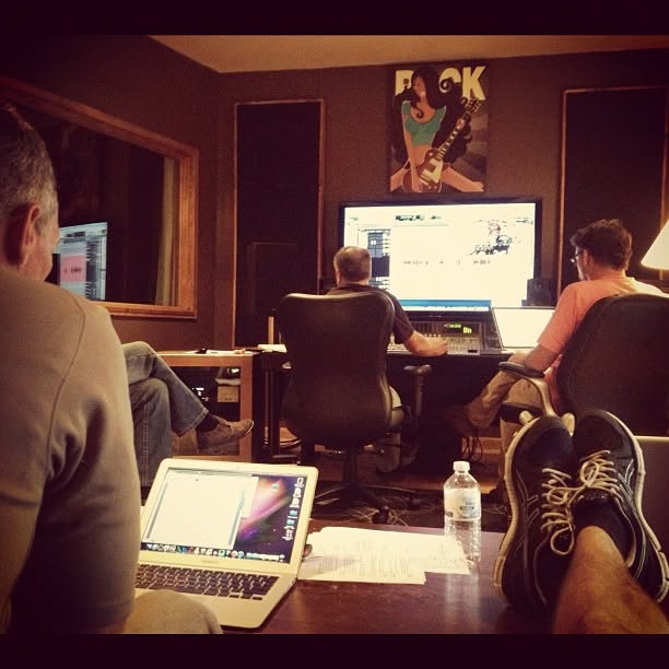A team reviewing a cut together in a dimly lit edit and mix suite