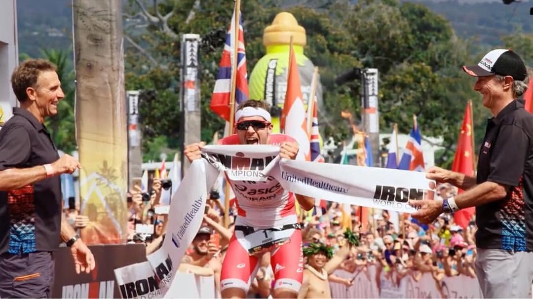 A triathlete breaking the tape at the IRONMAN World Championship finish line