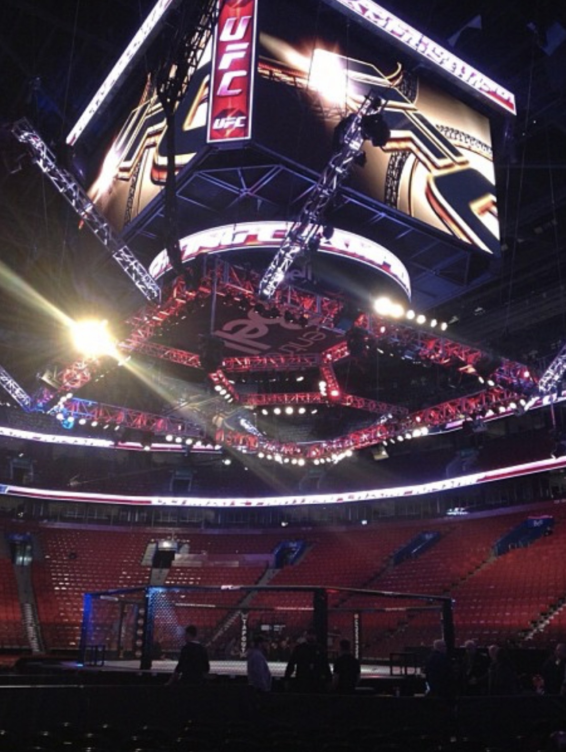 An empty arena rigged with lighting truss and video screens before a UFC event